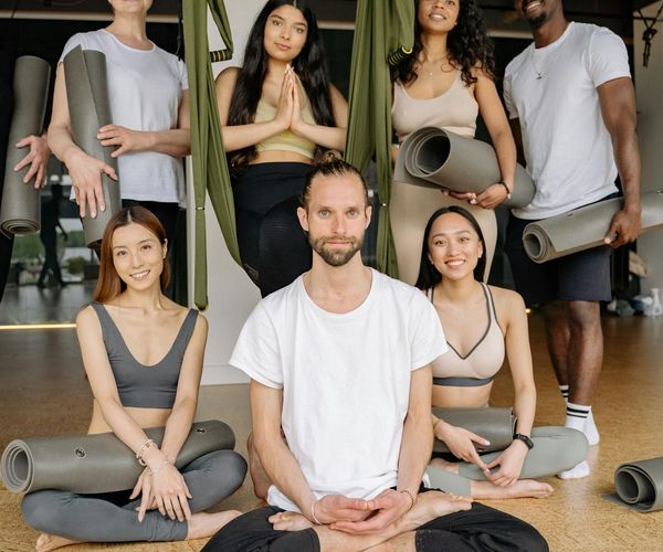 Diverse group of people smiling and preparing for a yoga class.